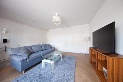 a living room with a blue couch and a flat screen tv at Modern 2 bed house in Hollystown with free parking in Dublin