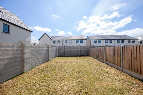 a backyard with a fence and a building at Modern 2 bed house in Hollystown with free parking in Dublin