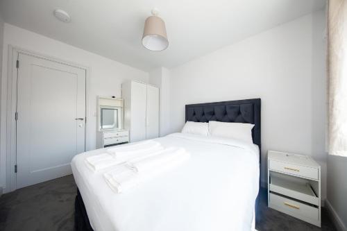 a white bedroom with a large bed with a black headboard at Modern 2 bed house in Hollystown with free parking in Dublin