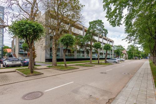 a street with trees and a building with cars on it at Golden Dunes Apartment in Palanga