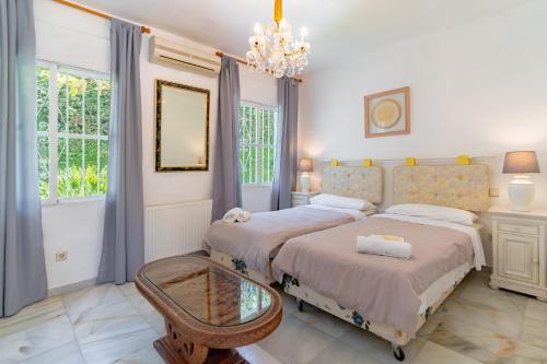 a bedroom with two beds and a chandelier at Beautiful Villa La Caracola in Marbella