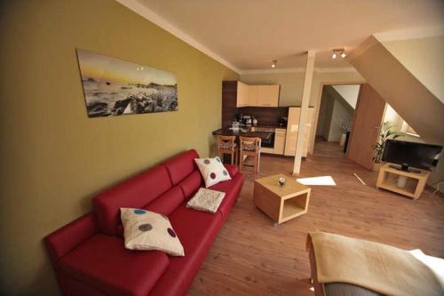 a living room with a red couch and a kitchen at Ferienappartements Jack _ Richies in Greifswald