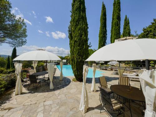 a patio with tables and umbrellas next to a pool at Ferienwohnung Fortuna del Lupo mit Pool und Aussicht in Subbiano