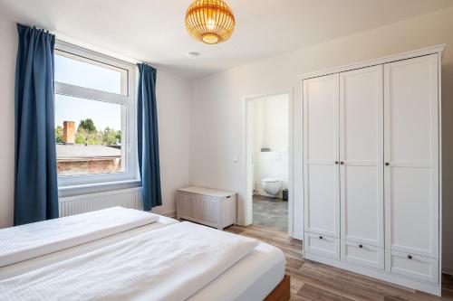 a white bedroom with a bed and a window at Haus Kreihnsdörp, Ferienwohnung 2 in Grevesmühlen