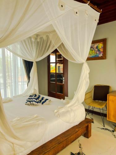 a bedroom with a canopy bed with white curtains at Japa Guesthouse in Canggu