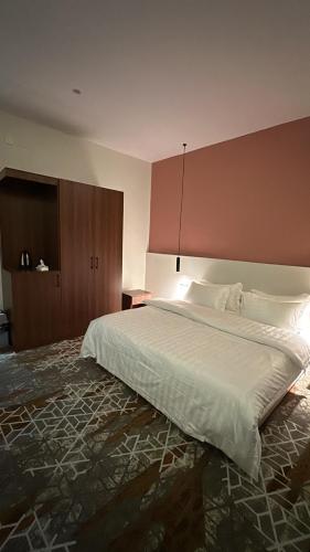 a bedroom with a large white bed and a brown wall at شقق دخول ذاتي in Taif