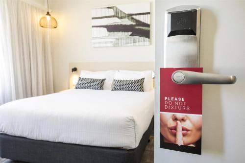 a bedroom with a bed with a sign next to it at Nightcap at Finsbury Hotel in Adelaide