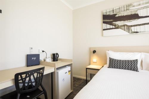 a small room with a bed and a desk at Nightcap at Finsbury Hotel in Adelaide
