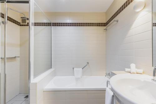 a white bathroom with a shower and a sink at Nightelier Mermaid Waters in Gold Coast