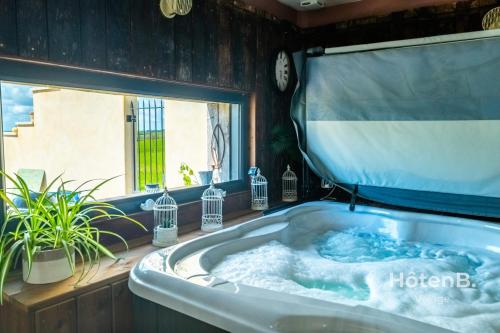 a jacuzzi tub in a room with a window at Cottage Mamie Yvette Private Spa in Blanc