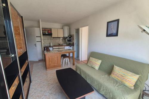 un salon avec un canapé vert et une cuisine dans l'établissement Apartment with pool - near beach, à Saint-Mandrier-sur-Mer