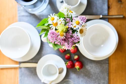 a table with white plates and a bouquet of flowers at Wirtseppelerhof Apartments in Leutasch