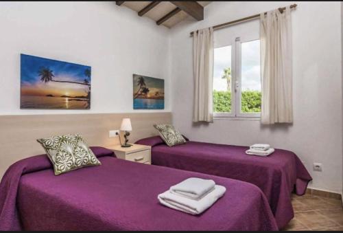 two purple beds in a room with a window at Villa Viola Bosch Menorca in Cala'n Bosch