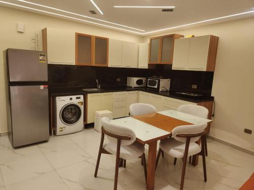 Una cocina con mesa y sillas y un refrigerador. en Porto marina for rent, en El Alamein