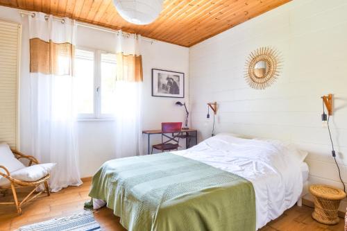 a bedroom with a bed and a chair and a window at À 800 m de la mer, jolie maison avec jardin pour 7 in LʼÉpine