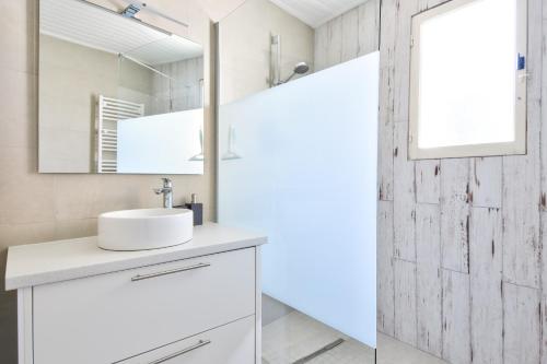 a white bathroom with a sink and a mirror at À 800 m de la mer, jolie maison avec jardin pour 7 in LʼÉpine