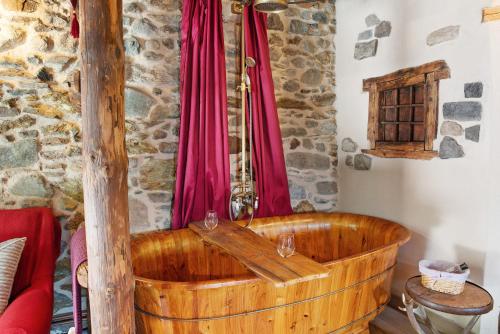 a wooden tub in a room with a red curtain at Camera Deluxe - Cuore Selvatico in Monno