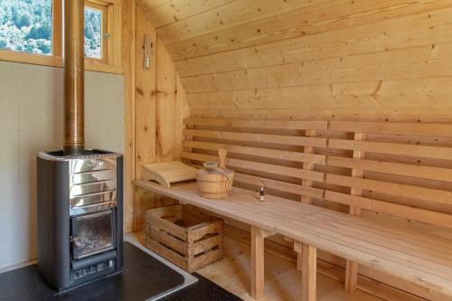 a wooden sauna with a bench and a stove at Camera Deluxe - Cuore Selvatico in Monno