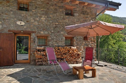 a patio with a table and two chairs and an umbrella at Camera Deluxe - Cuore Selvatico in Monno