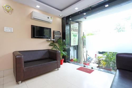 a living room with a leather couch and a tv at Collection O Greenpark in Jamshedpur