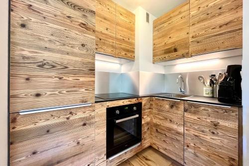- une cuisine avec des placards en bois et un four dans l'établissement Apartment with balcony in the heart of Megève, à Megève