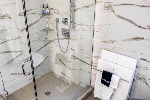 a bathroom with a shower with white marble walls at SKKY Hotel in Whitehorse