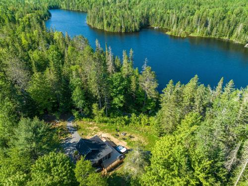 an aerial view of a cabin in the woods next to a lake at Spa pool Private Lake - Chalet Hello in Saint-Alphonse-Rodriguez