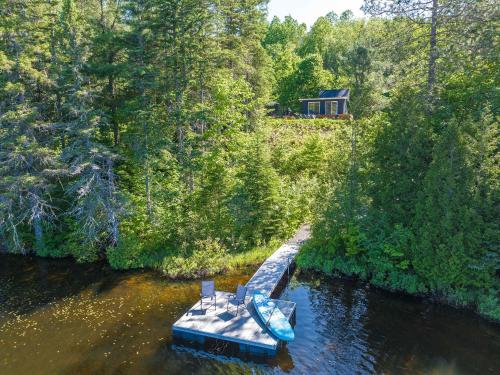 a blue boat in the water with a house in the background at Spa pool Private Lake - Chalet Hello in Saint-Alphonse-Rodriguez