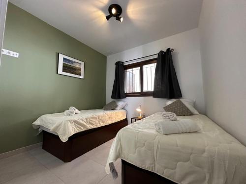 Un dormitorio con dos camas y una ventana. en Apartamento moderno cerca de la playa, aire acondicionado, 2 dormitorios, jardín común - ES-376-18, en Pulpí