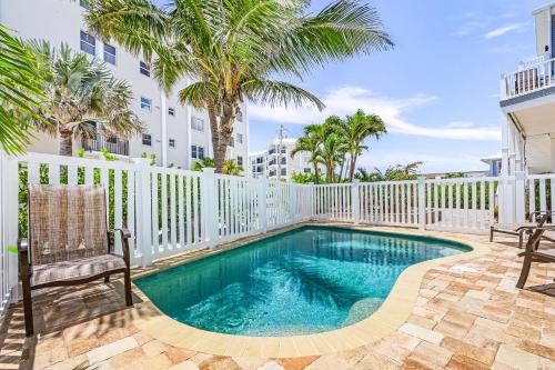 a swimming pool with a white fence and palm trees at Luxury Beach Front Pool Home in Paradise! home in Fort Myers Beach