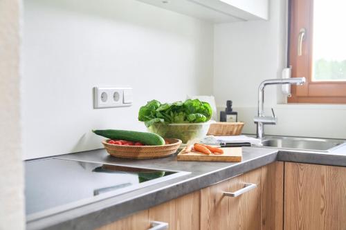 a kitchen with a sink and vegetables on a counter at Wirtseppelerhof Apartments in Leutasch