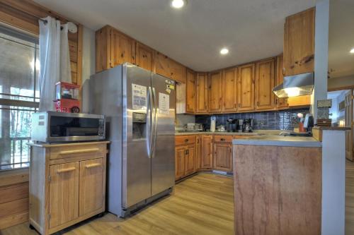 a kitchen with a stainless steel refrigerator and wooden cabinets at Moon Tower Cabin - Beautiful Water Views Firepit More in Blairsville