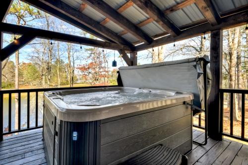 a hot tub on the deck of a porch at Moon Tower Cabin - Beautiful Water Views Firepit More in Blairsville