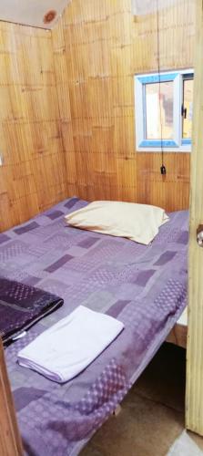 a bedroom with a bed with purple sheets and a window at PINOY YOGA POLE PIYOPO LA UNION fan kubo 4 pax in Rimus
