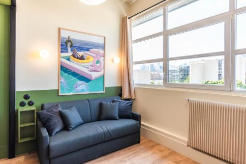 a living room with a couch and two windows at Maison Delage in Courbevoie