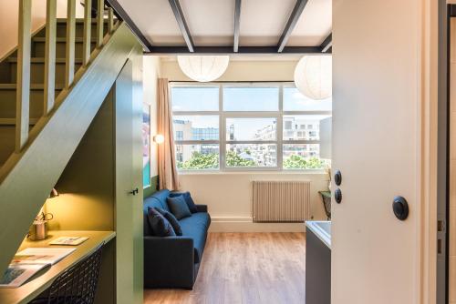 a living room with a blue couch and a staircase at Maison Delage in Courbevoie