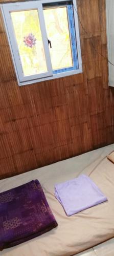 a bed with two purple sheets and a window at PINOY YOGA POLE PIYOPO LA UNION fan kubo 4 pax in Rimus