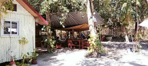 a patio with a table and chairs under a tree at PINOY YOGA POLE PIYOPO LA UNION fan kubo 4 pax in Rimus