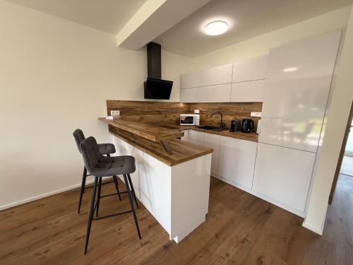 a kitchen with white cabinets and a bar with a stool at Objev Jeseníky Velké Losiny in Velké Losiny