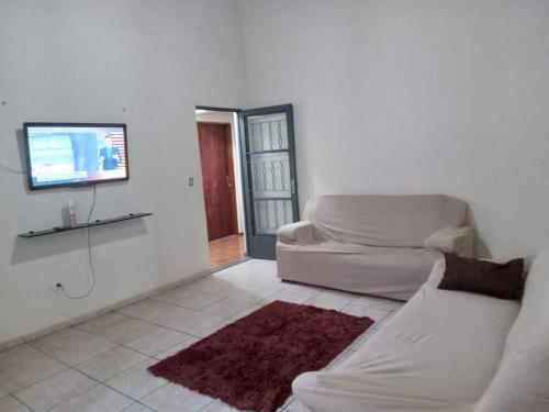 a white living room with a couch and a tv at Hospedagem Alvinópolis in Atibaia