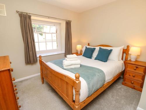 ein Schlafzimmer mit einem großen Holzbett mit blauen Kissen in der Unterkunft Stable Cottage in Ventnor