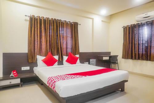 a bedroom with a large bed with red pillows at Hotel O Paradise Inn Talegaon Dabhade in Pune