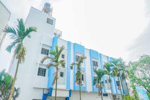 a building with palm trees in front of it at Hotel O Paradise Inn Talegaon Dabhade in Pune