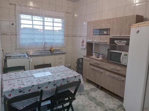 a kitchen with a table and a table and a refrigerator at Hospedagem Alvinópolis in Atibaia