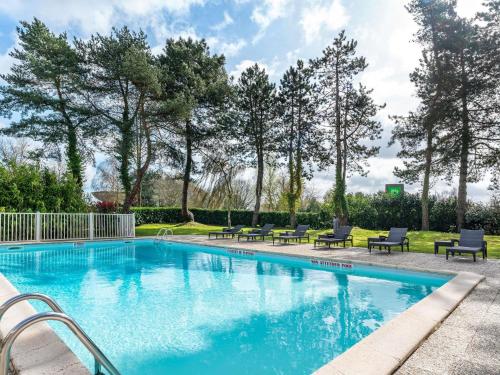 a swimming pool with chairs and trees in a yard at Ibis Styles Lisieux Normandie in Lisieux