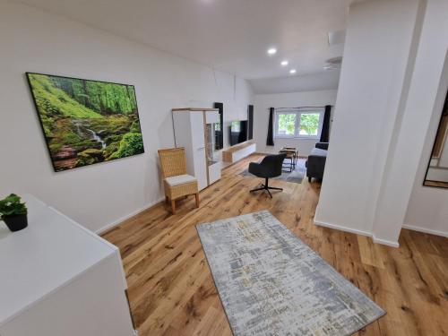 a living room with white walls and wooden floors at FEWO am Rathaus in Heimbach