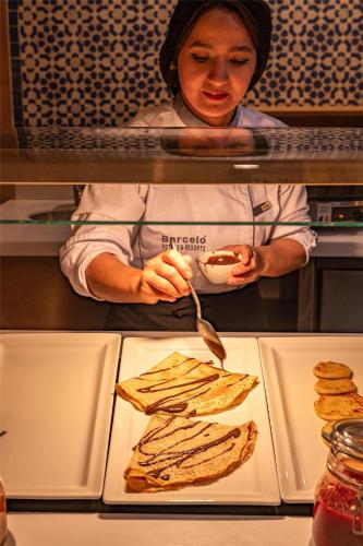 a woman is preparing a plate of grilled sandwiches at Barceló Fès Medina in Fez