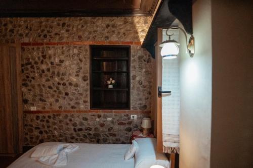 a bedroom with a brick wall and a bed with a window at Kulla Inglizit in Shkodër