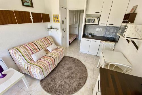 un salon avec un canapé et une cuisine dans l'établissement Charming studio near the harbour, à Mauguio