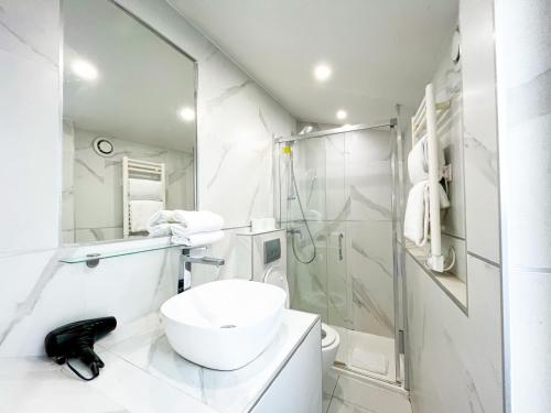une salle de bain blanche avec un lavabo et une douche dans l'établissement 115 - Urban Vuitton Saint Denis, à Paris